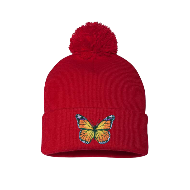 Red cuffed beanie with a Pom Pom. it has an embroidered butterfly with a mix of colors yellow, orange, green, blue and white