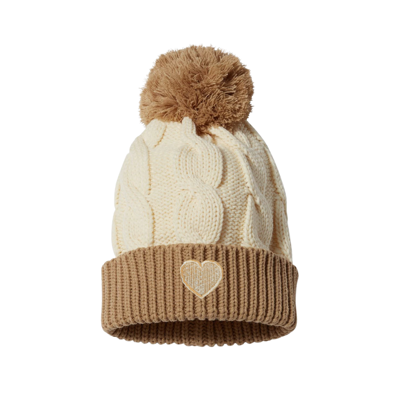 Chunky cuffed cable beanie with a pom pom. It is creme and the cuff and the pom pom are beige. it has a creme heart embroidered on the cuff