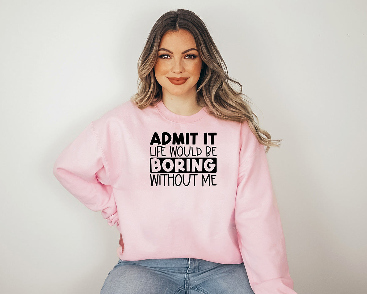 Woman wearing a light pink sweatshirt. Screen printed transfer in big black letters on the front. Admit it in bold caps life would be in caps boring in bold caps without me in caps