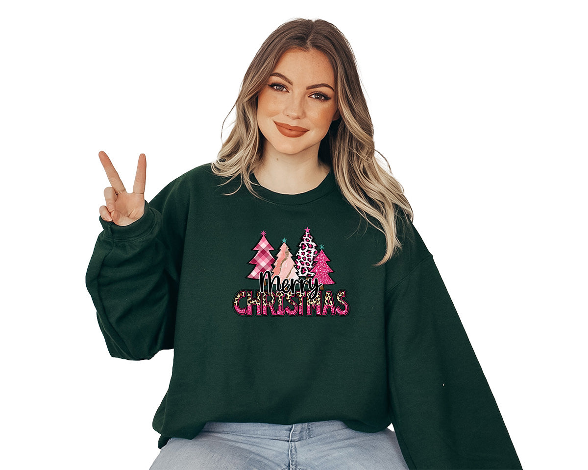 Young lady wearing a forest green sweater with a big screen printed on the front. This one has four different pink Christmas trees and a text in black Merry and Christmas in pink and cheetah colors