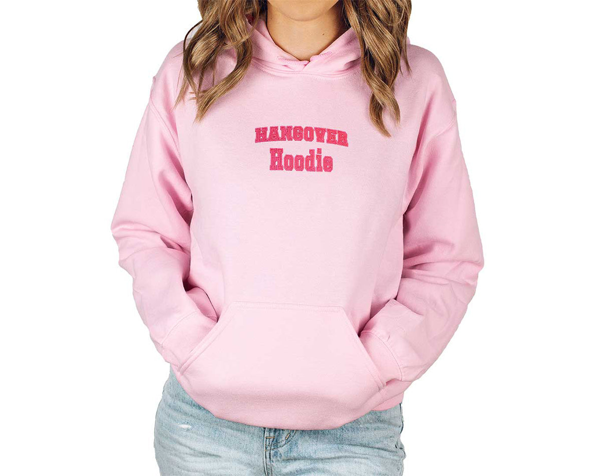 Young lady wearing a light pink comfortable hoodie. Hangover Hoodie embroidered with pink thread color