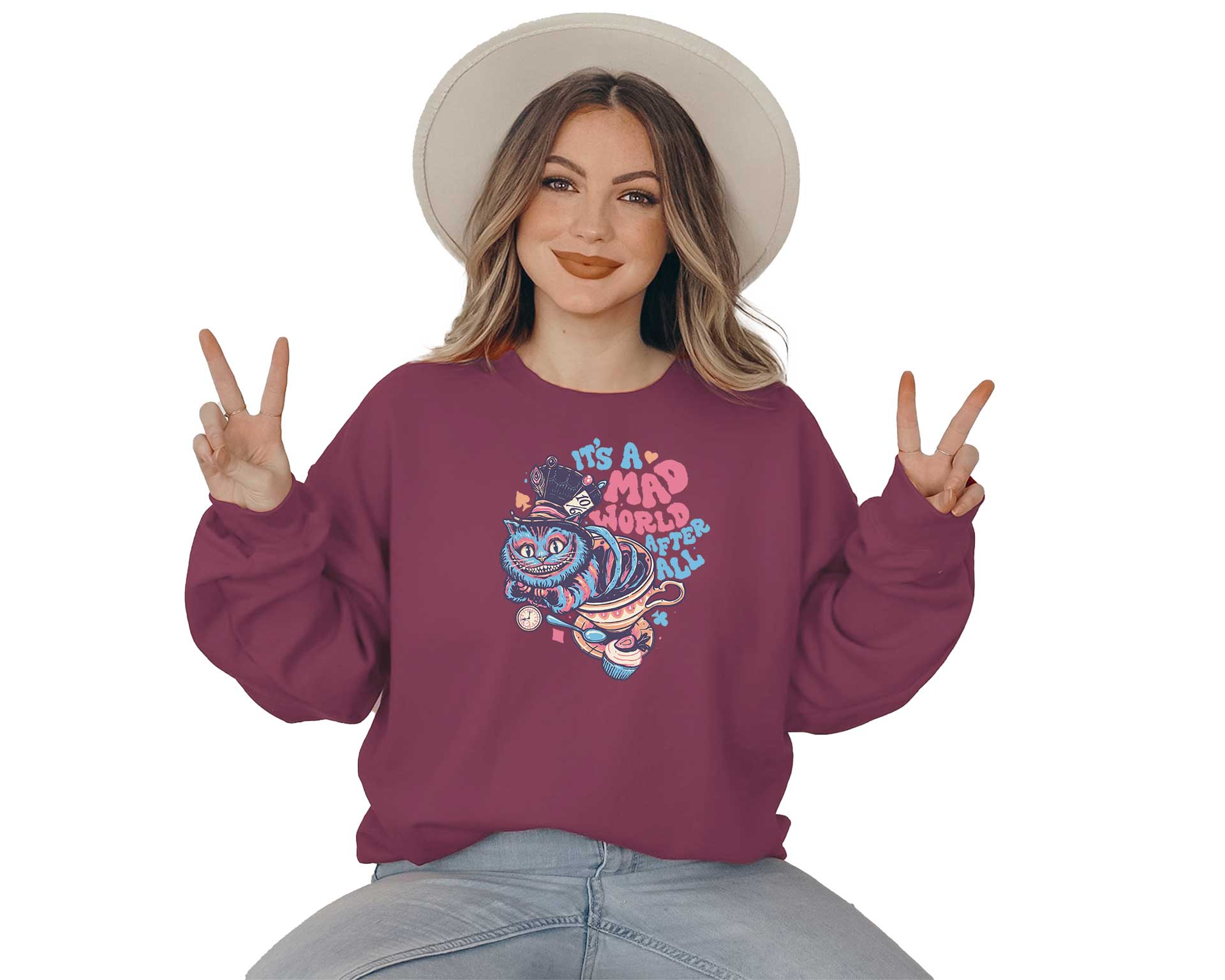 Young lady wearing a garnet crewneck sweatshirt with a screen printed. A big colorful smiley cat with a text it is a mad world after all