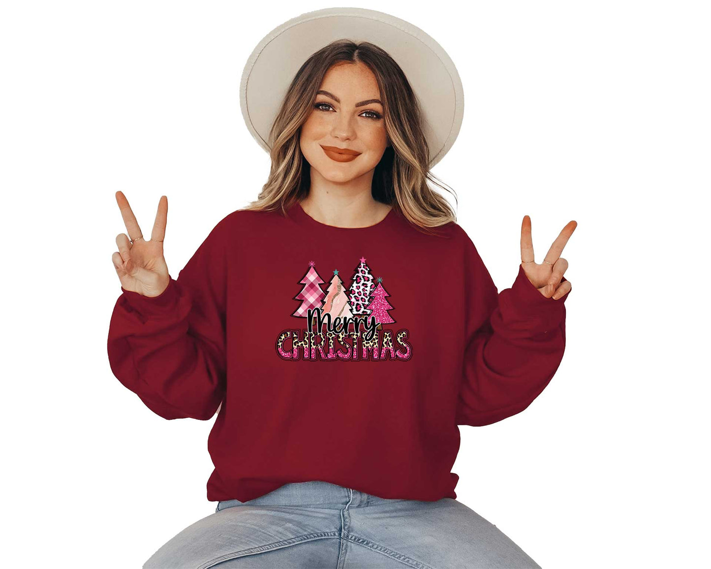 Young lady wearing a garnet  sweater with a big screen printed on the front. This one have four different pink Christmas trees and a text in black Merry and Christmas in pink and cheetah colors