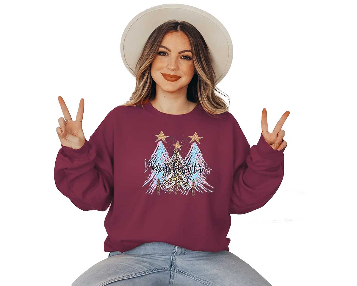 Young lady wearing a garnet sweatshirt with a large screen printed. Three Christmas trees with colors of blue and pink and a text of merry Christmas