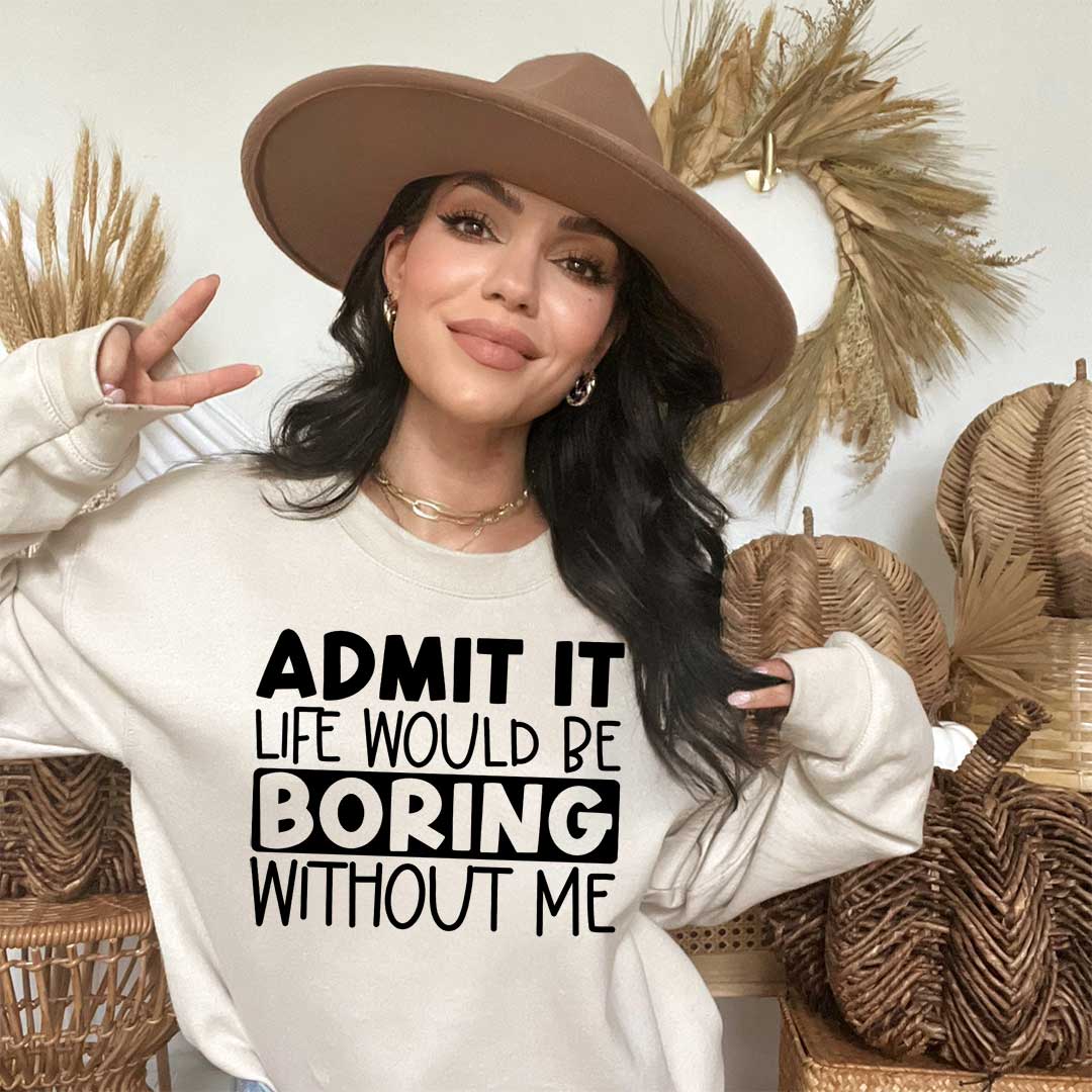 Woman wearing a sand sweatshirt. Screen printed transfer in big black letters on the front. Admit it in bold caps life would be in caps boring in bold caps without me in caps