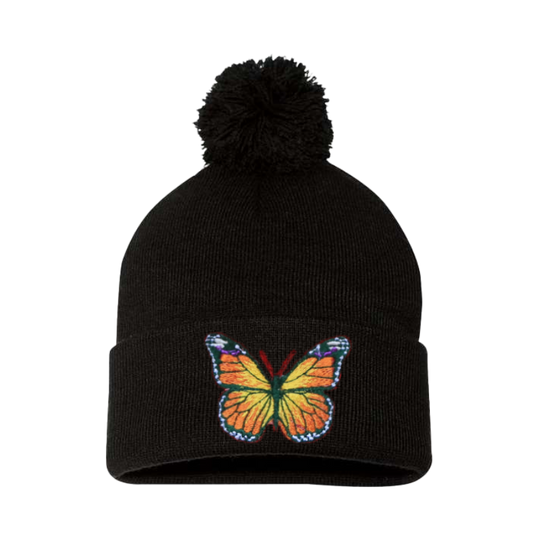 Black cuffed beanie with a Pom Pom. it has an embroidered butterfly with a mix of colors yellow, orange, green, blue and white