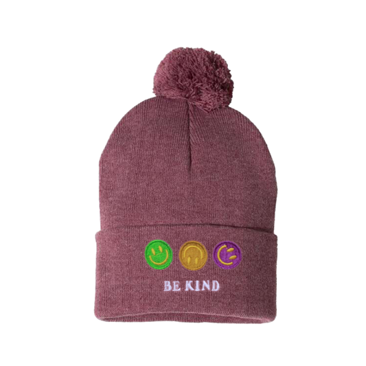 Heather cardinal cuffed beanie with a pom pom. It has an embroidery on the cuff  of three happy faces, green, gold and purple and a text in caps  Be kind