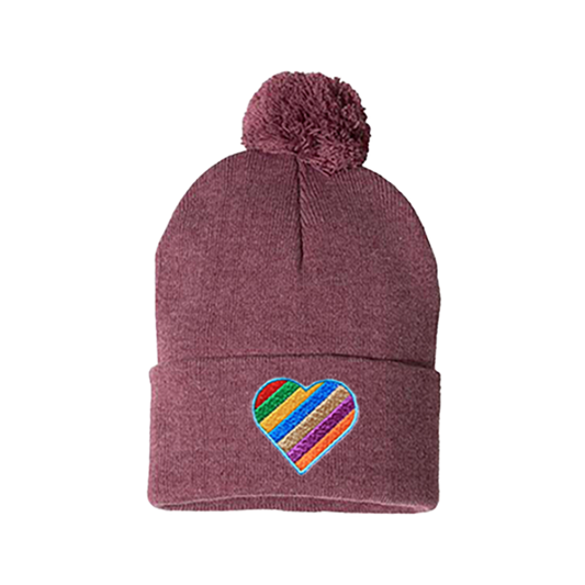 Heather cardinal cuffed beanie with a pom pom. It has a heart embroidered with the  Pride colors on the cuff