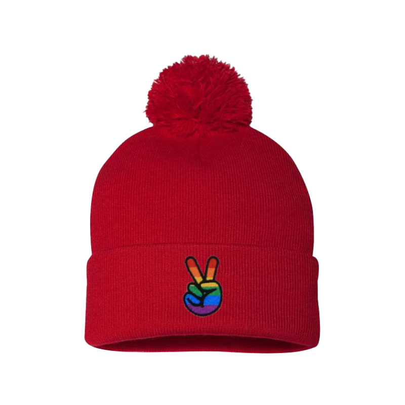 Red cuffed beanie with a pom pom. It has embroidered the sign of peace on the cuff with the Pride colors