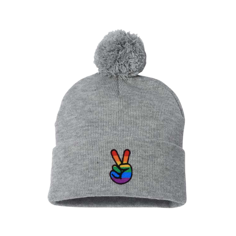 Light Gray cuffed beanie with a pom pom. It has embroidered the sign of peace on the cuff with the Pride colors